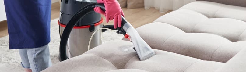 Image of a professional cleaner cleaning a sofa